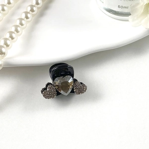 Close-up of black heart-shaped hair claw clip with faceted gem and rhinestones