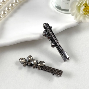 Dettaglio di fermagli per capelli vintage in lega scura con strass grigio fumo e base