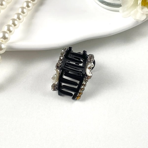 Close-up of a mini pearl and rhinestone hair claw clip on a white decorative plate