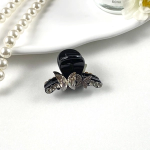 Macro detail of elegant black hair claw clip featuring shimmering silver rhinestone butterfly