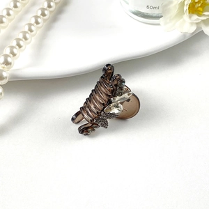 Detailed close-up of a mini hair claw clip with rhinestones on a white ceramic plate