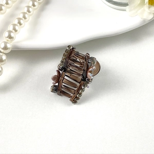 Close-up of brown resin hair claw clip with delicate rhinestone flowers on white background