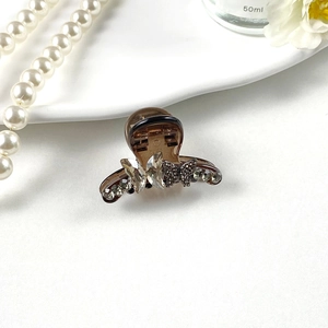 Close-up of sparkling rhinestone butterfly hair claw clip with elegant brown resin base