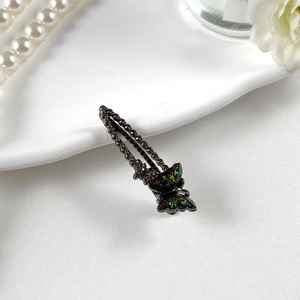 Dettaglio del fermaglio a farfalla gotico con paillettes iridescenti e strass scuri
