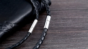 Close-up of black braided leather necklace cord with polished silver magnetic clasp