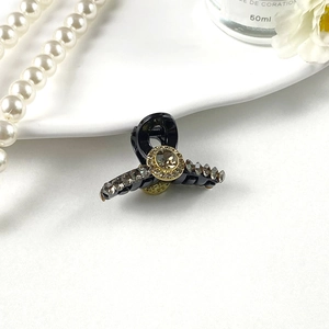Close-up of a mini black hair claw with sparkling rhinestones on a white porcelain plate