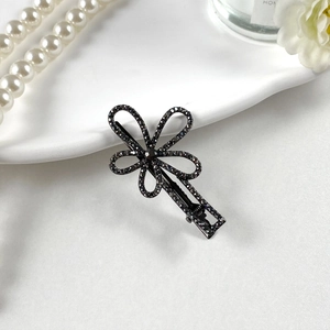 Dettaglio di un fermaglio per capelli a fiore scuro in lega con strass neri brillanti