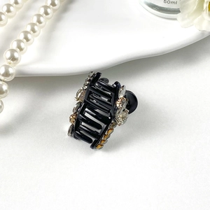 Close-up of elegant mini hair claw clip with rhinestones on a decorative white background