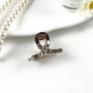 Macro shot of an amber mini hair claw clip with sparkling rhinestones on a ceramic tray