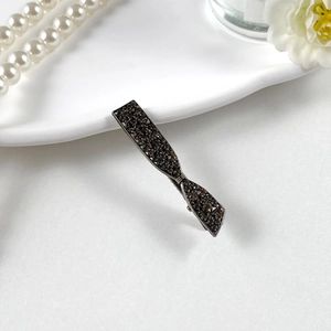 Dettaglio del fermaglio per capelli in lega con strass grigio scuro e forma a fiocco