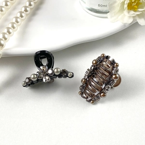 Detailed view of hair claws with rhinestones and pearls on elegant white display tray