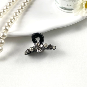 Close-up of black hair clip featuring sparkling rhinestones and pearl flower arrangement