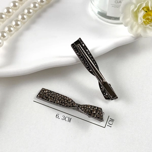 Dettaglio dei fermagli per capelli a fiocco in lega scura con strass su vassoio, 6,3 cm