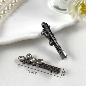Dettaglio di fermagli per capelli grigi con strass e indicazione della misura 6,3 cm