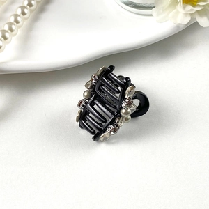 Close-up of elegant mini hair claw clip with inlaid pearls and sparkling rhinestones
