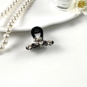 Detailed view of elegant black hair claw clip with rhinestones and faux pearls