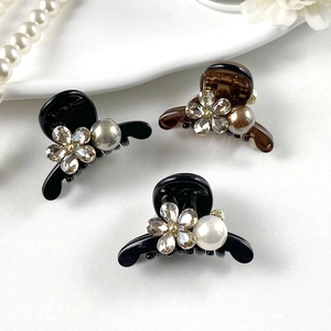 Detail of three floral hair clips with sparkling rhinestones and elegant pearls
