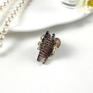 Detailed view of elegant amber resin hair claw clip with golden flower trim on white background