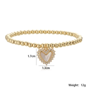Détail du pendentif cœur avec nacre et zircons sur un bracelet en perles dorées