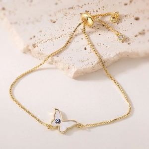 Détail d'un bracelet papillon plaqué or 18K avec nacre blanche et incrustation œil bleu