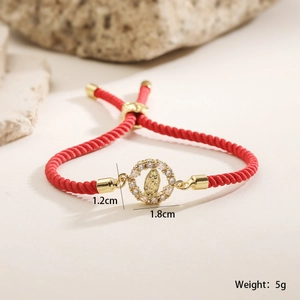 Detailed macro view of red braided rope bracelet with gold Virgin Mary pendant and zircons