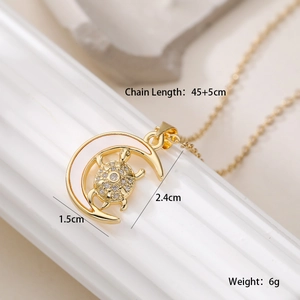Detailed close-up of 18K gold turtle crescent pendant with white zircon inlays