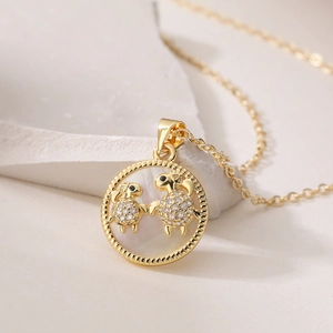 Macro shot of 18K gold tortoise pendant with white mother-of-pearl and crystals