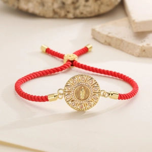 Detailed macro view of 18K gold plated Virgin Mary charm with zircons on red rope bracelet