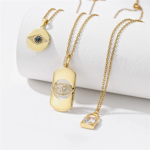 Tres collares dorados con colgantes de ojo y candado en soportes cilíndricos blancos