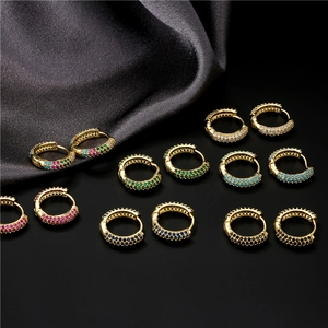 Gros plan de boucles d'oreilles huggie dorées serties de zircons colorés micro-pave