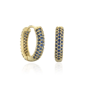 Détails macro de boucles d'oreilles huggie dorées avec trois rangées de zircons bleus