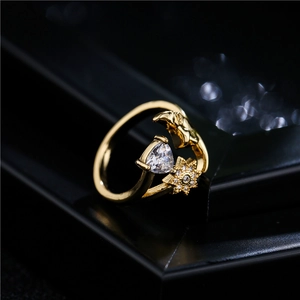 Golden open ring with heart-shaped zircon and sparkling star on black background