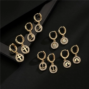 Detalle de set de pendientes de aro bañados en oro de 18K con colgantes de circón micro