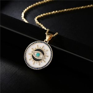 Golden Evil Eye pendant necklace with blue crystals and white enamel on a black display