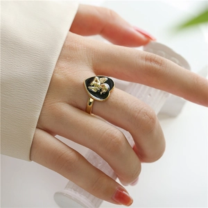 Close-up of heart-shaped black enamel ring with golden cupid angel on hand