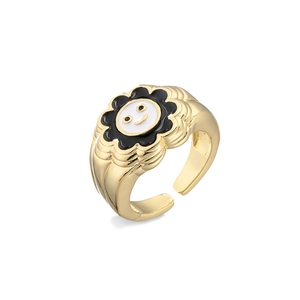 Close-up of gold-plated sunflower ring featuring a black and white enamel smiley face charm