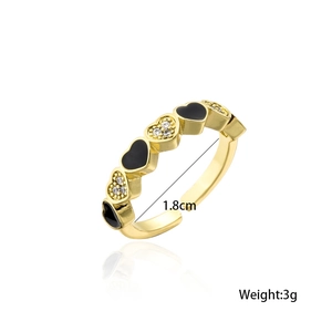 Vue détaillée de la bague dorée avec motifs de cœurs en émail noir et zircons