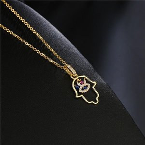 Vue macro du pendentif Main de Fatma dorée avec zircons sur fond de cuir noir