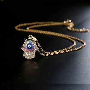 Collier main de Fatma dorée avec pendentif œil maléfique et zircons sur fond texturé noir