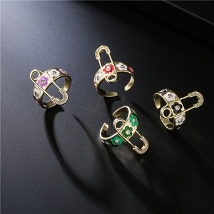 Set of four gold open rings with enamel flowers and zircon safety pin accents on black background