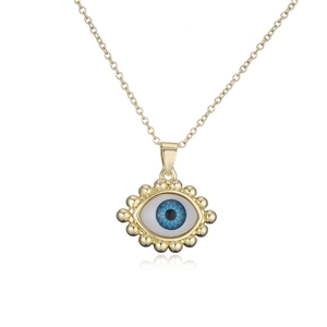 Macro shot of 18K gold plated evil eye pendant with blue inlay and beaded edge detail