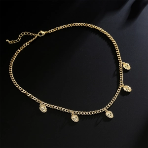Collier gourmette plaqué or style hip hop avec cinq pendentifs tête de mort aux yeux verts