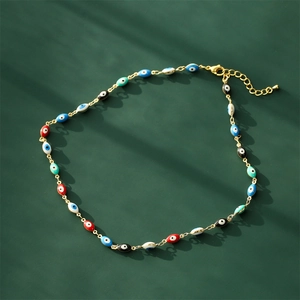 Gold-plated Evil Eye necklace with colorful enamel olive beads on a dark green surface