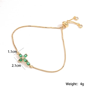 Detail view of 18K gold-plated cross bracelet with green gems and adjustable slide clasp
