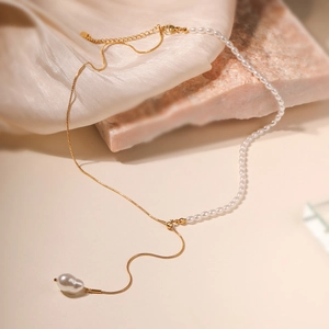 Elegant gold chain and pearl necklace with baroque pendant on silk background