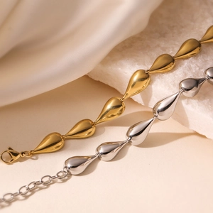 Polished teardrop link necklaces in gold and silver finish on white silk background