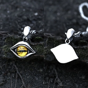 Vintage stainless steel devil eye pendant with yellow eyeball detail on dark rock background