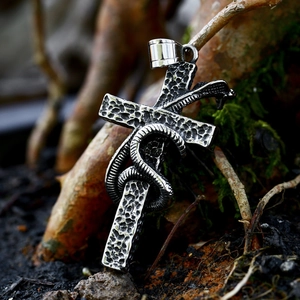 Vintage stainless steel snake and cross pendant with hammered texture on a nature branch