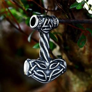 Détail du pendentif Viking Mjölnir avec symbole Valknut sur une branche d'arbre naturelle