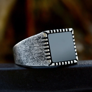 Macro shot of vintage stainless steel men's ring with square black stone and aged finish